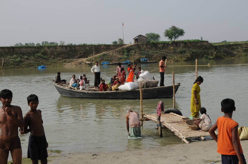Families and children beside floodwater as a boat carries people and their belongings during the 2008 Bihar floods