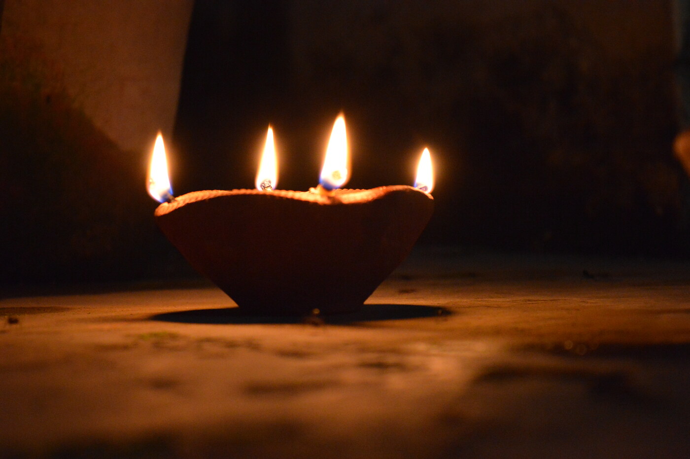 A traditional earthen oil lamp with glowing flames during Diwali