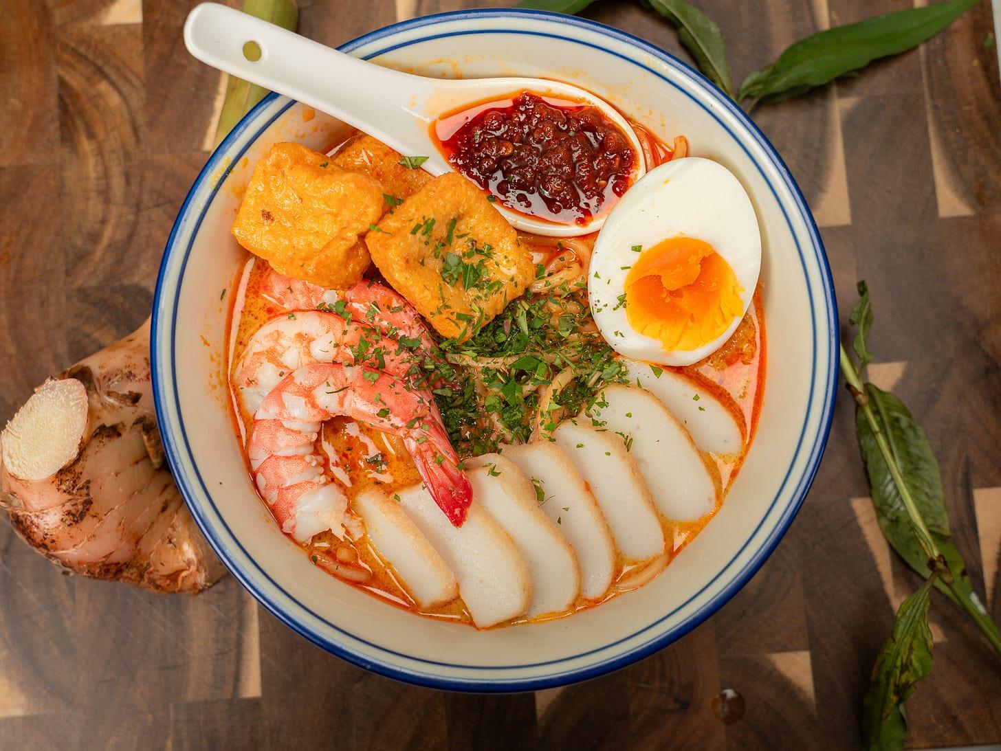A bowl of Singapore laksa with noodles, prawns and spicy coconut broth
