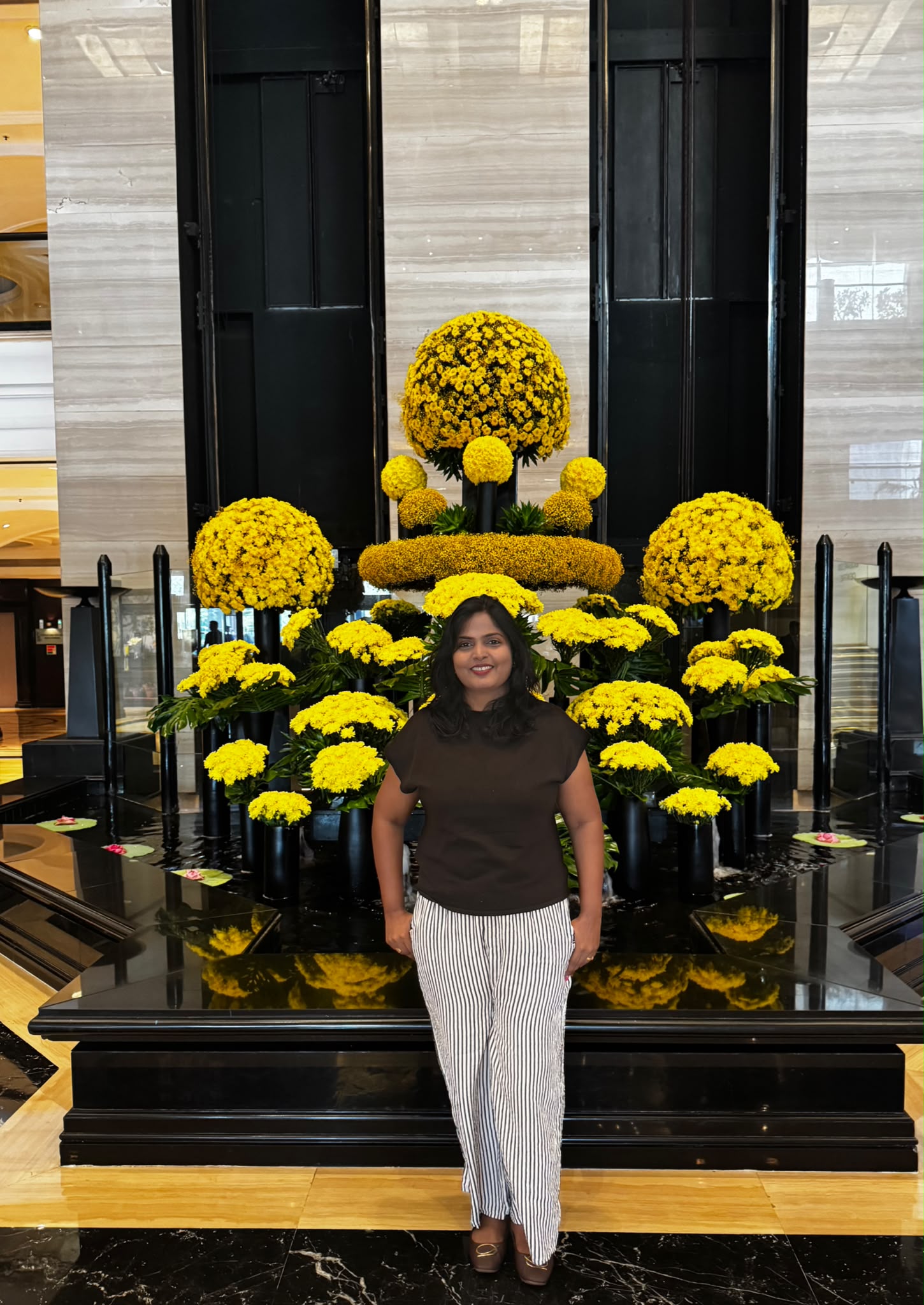 A visitor beside a yellow floral display at Taj Lands End