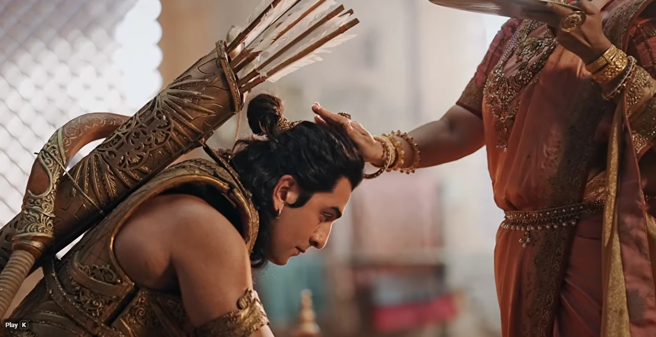A man dressed as Lord Ram bows his head as another person blesses him.
